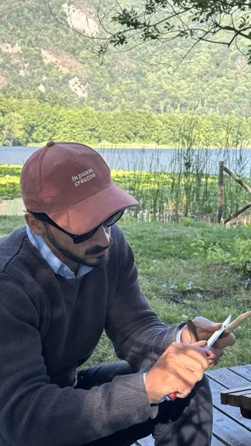 Luigi Nigro con il cappello seduto all'aperto in riva al lago